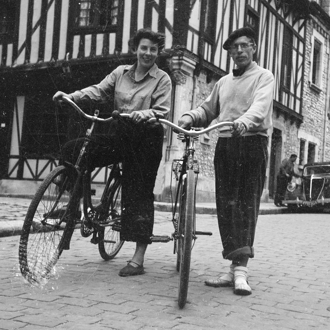 Svartvitt fotografi på Monica Schildt och Noël Tinayre med cyklar i Moret-sur-Loing 1948. Ur SLS arkiv.